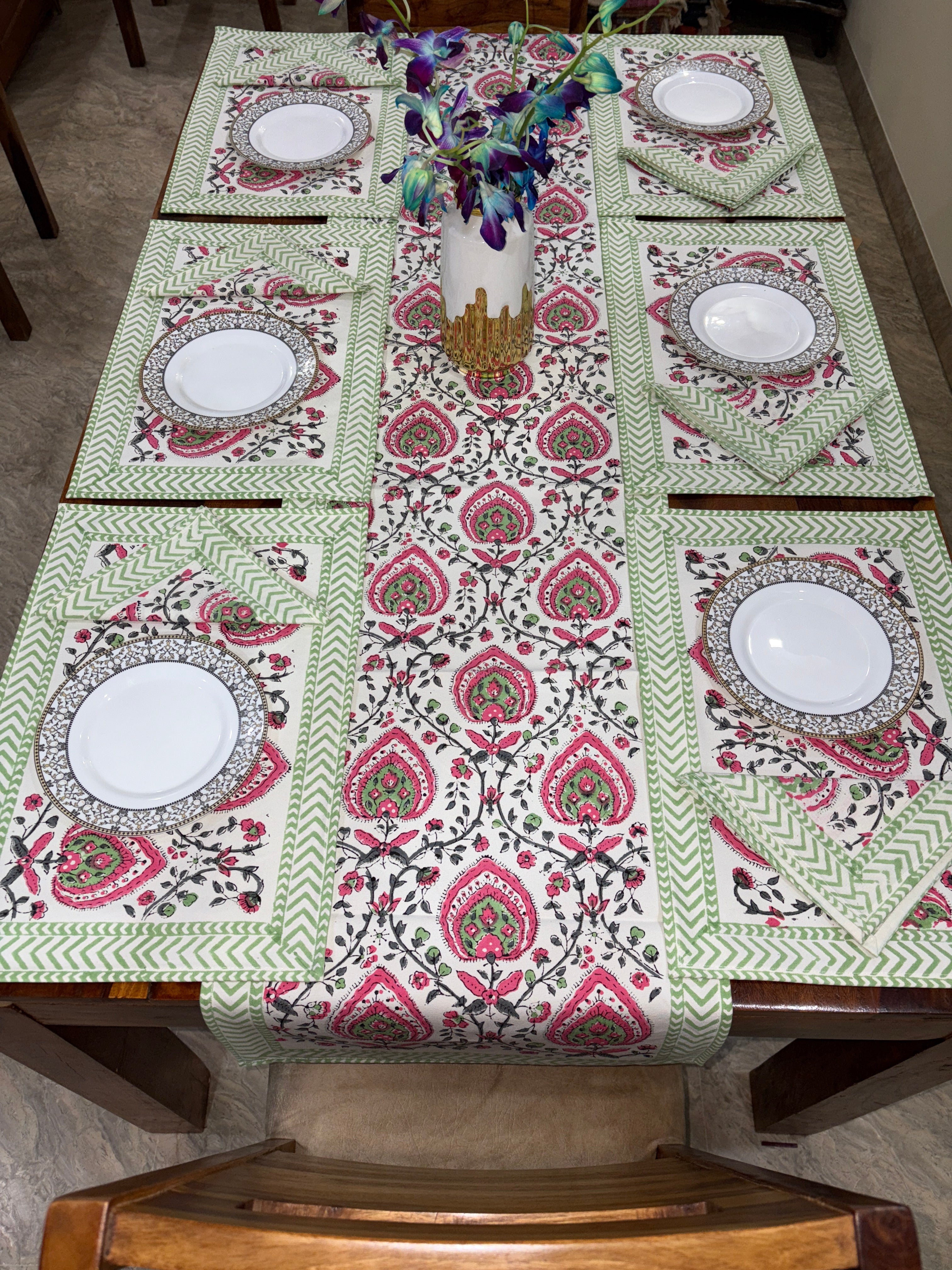 Dresser with a patterned cover featuring white plates on a wooden floor.