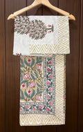 Decorative bedsheet with floral and geometric patterns on a wooden hanger against a wooden background.