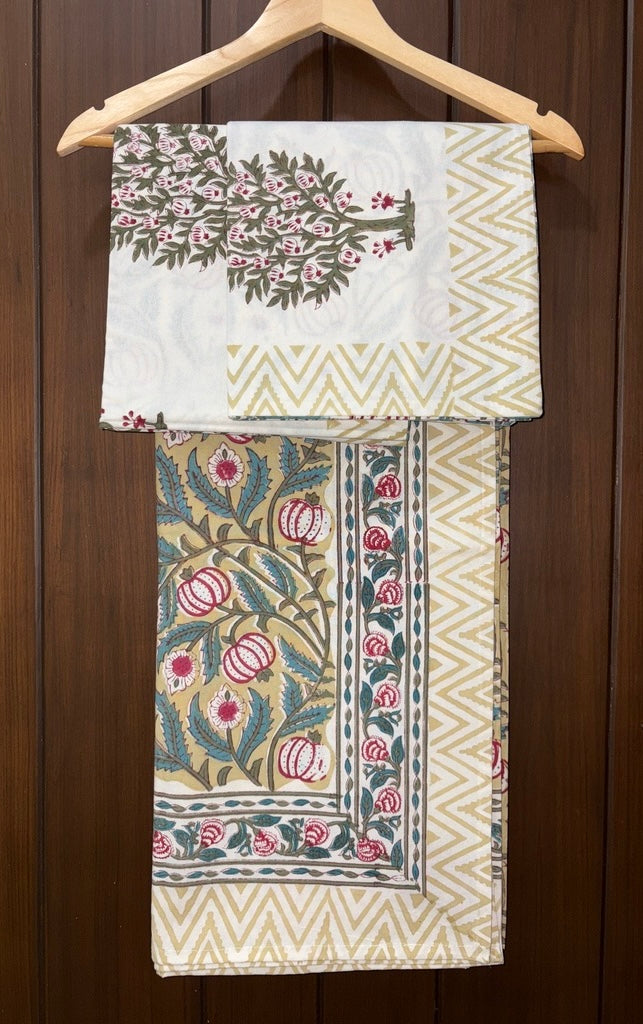 Decorative bedsheet with floral and geometric patterns on a wooden hanger against a wooden background.