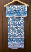 Set of blue and white patterned bedsheet hanging on a wooden hanger against a wooden background.