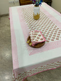 Decorative pink and white tablecloth with floral patterns on a wooden surface.