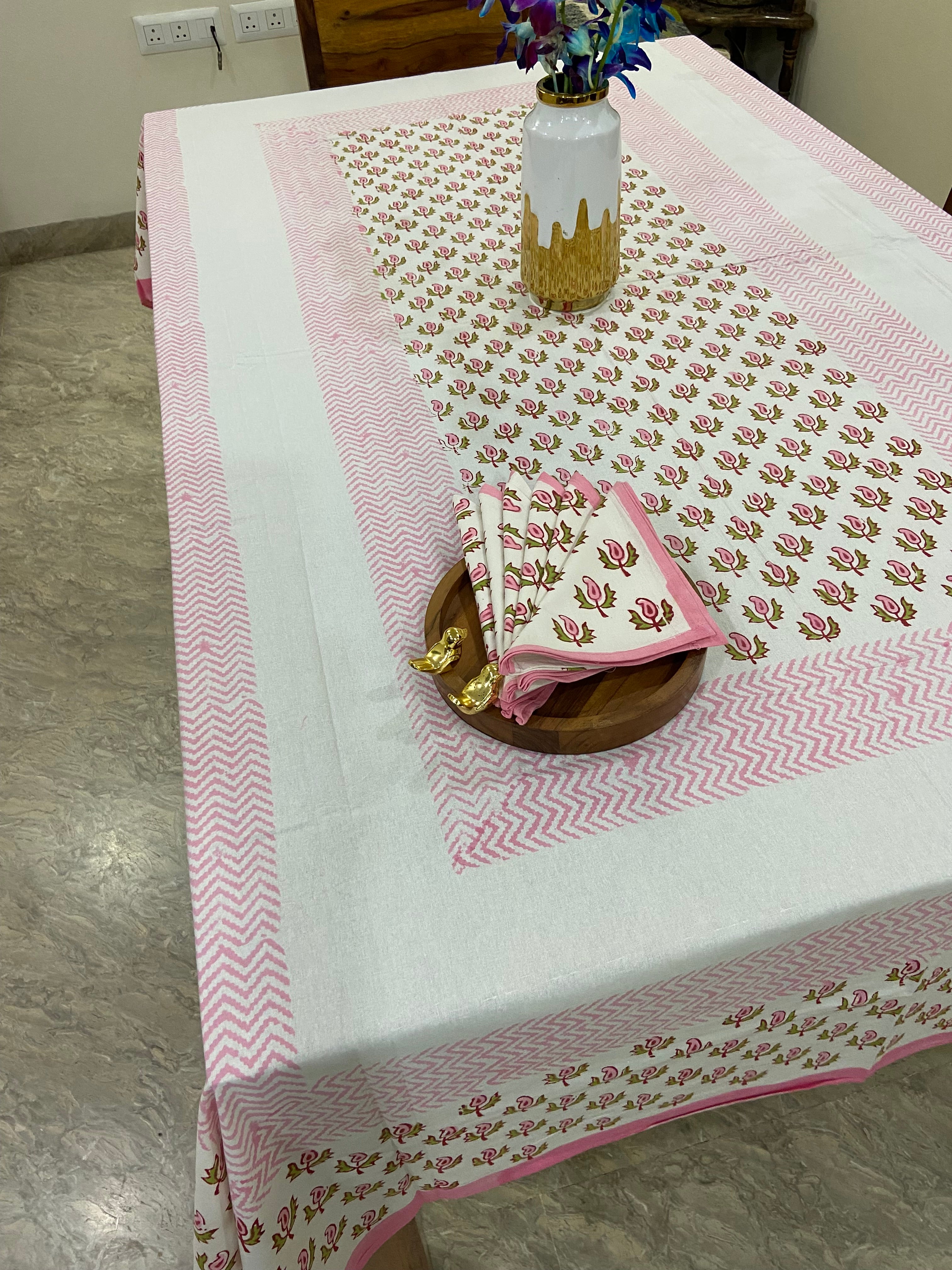 Decorative pink and white tablecloth with floral patterns on a wooden surface.