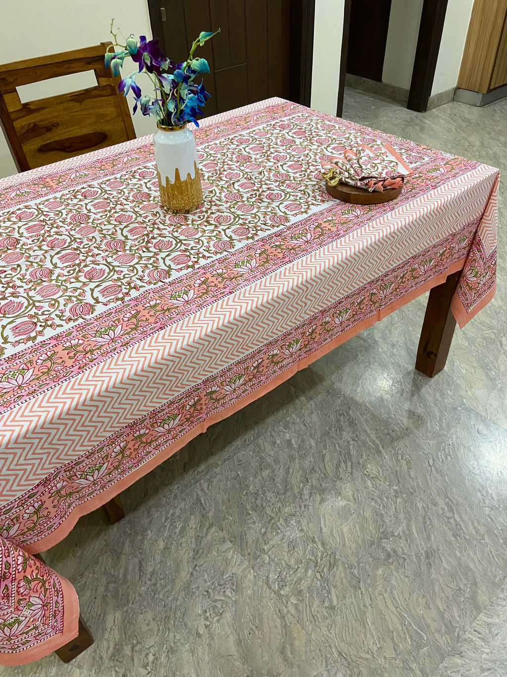Tablecloth with intricate pink and white patterns on a wooden table.