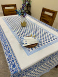 Decorative blue and white patterned tablecloth on a table with a wooden frame and floral decorations.