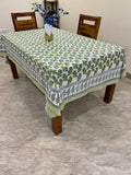 Table with a green and white patterned tablecloth on a marble floor.